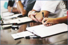 The photo shows a student taking notes for another student.