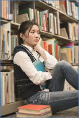 The photo shows a student siting on library floor, staring into space and looking depressed.