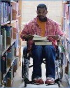 The photo shows a picture of a male student in wheelchair in a library.