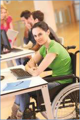 The photo shows a classroom with a female student sitting in a wheelchair.